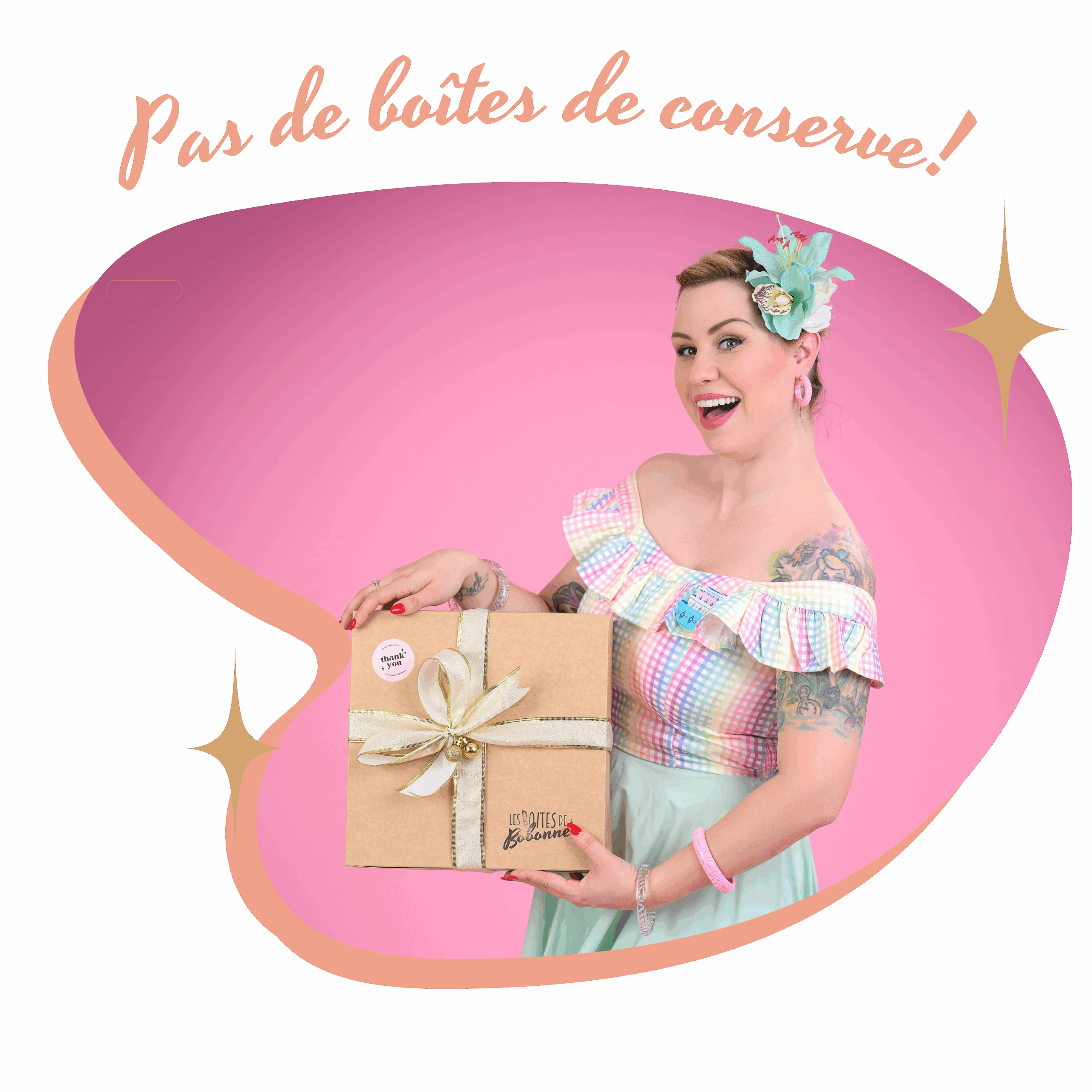 femme habillée en pinup tient un bébé et une box en kraft dans les bras. Elles sont toutes les deux très souriantes.